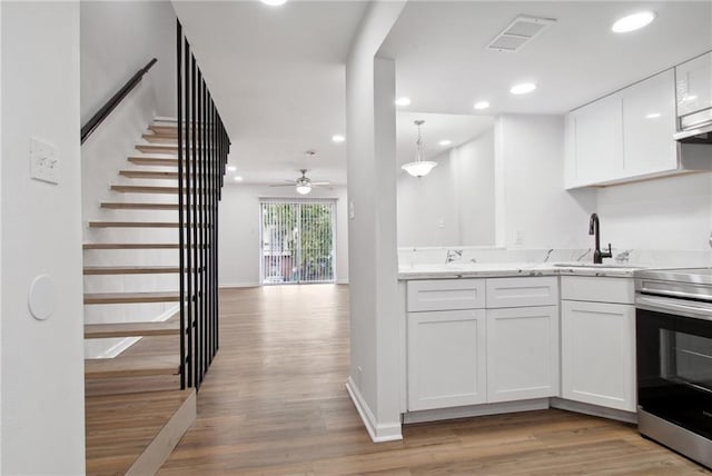 kitchen featuring light hardwood / wood-style flooring, stainless steel electric range oven, white cabinets, and ceiling fan