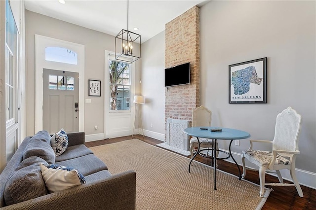 living room with dark hardwood / wood-style floors, a notable chandelier, and a fireplace