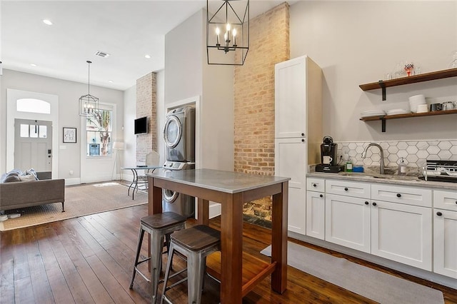 kitchen featuring hanging light fixtures, white cabinets, dark wood-type flooring, light stone countertops, and an inviting chandelier