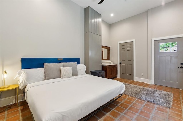 bedroom featuring connected bathroom, ceiling fan, a high ceiling, and tile patterned flooring