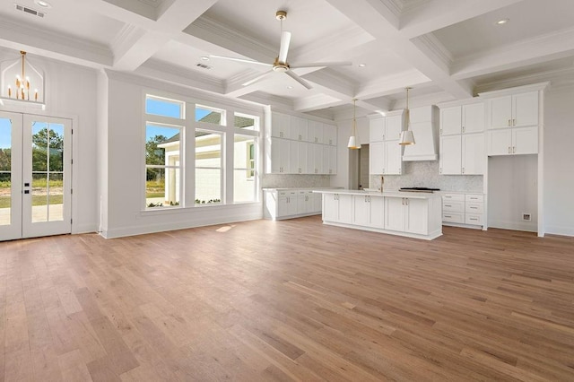 kitchen with a kitchen island, light hardwood / wood-style floors, beam ceiling, white cabinetry, and ceiling fan with notable chandelier