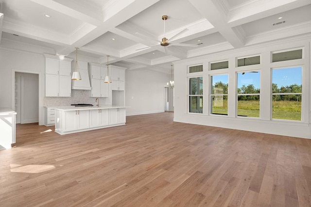 unfurnished living room featuring light hardwood / wood-style flooring, beamed ceiling, coffered ceiling, and crown molding