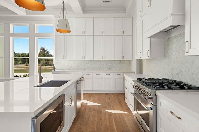 kitchen with sink, stainless steel appliances, pendant lighting, custom exhaust hood, and crown molding