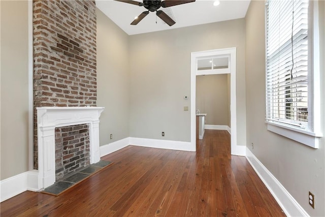 unfurnished living room featuring ceiling fan, dark hardwood / wood-style floors, and a fireplace