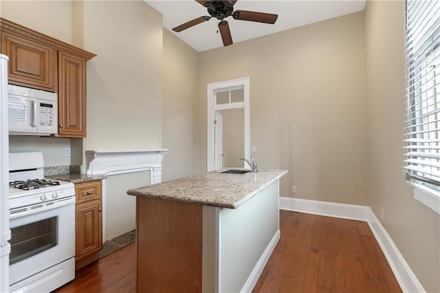 kitchen featuring dark wood-type flooring, sink, a center island with sink, ceiling fan, and white appliances