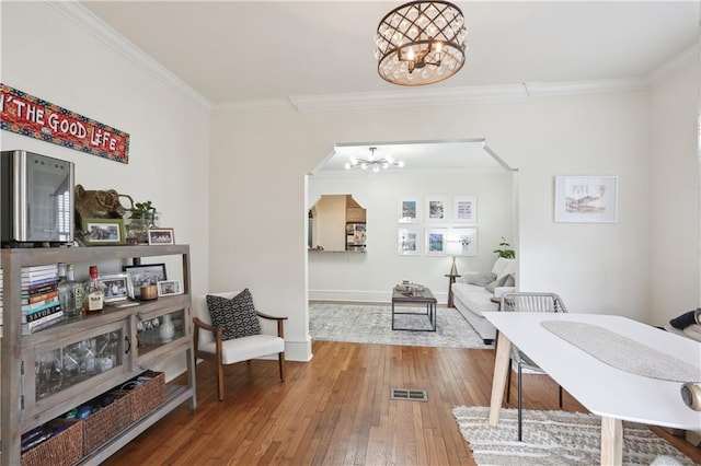 office area with wood-type flooring, ornamental molding, and a notable chandelier