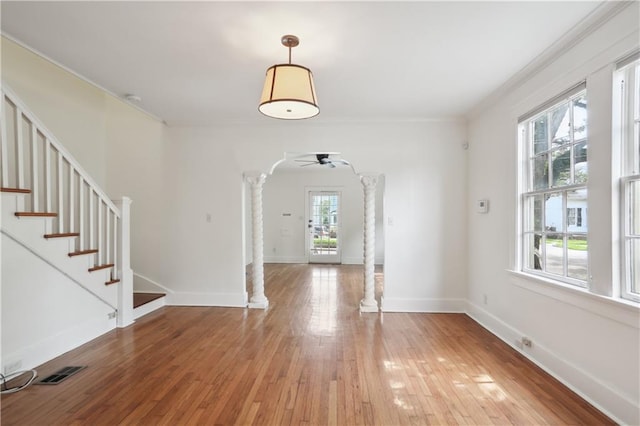 entryway with decorative columns, wood-type flooring, a wealth of natural light, and ceiling fan