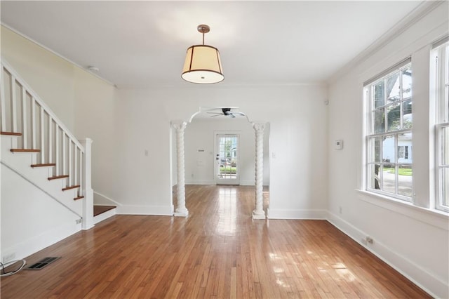 2900-04 Esplanade Ave, New Orleans, LA 70119 - unfurnished dining area featuring ornate columns, ornamental molding, light wood-style flooring, ceiling fan, and stairway