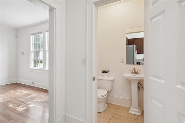 bathroom with ornamental molding, toilet, and hardwood / wood-style floors