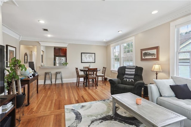 living room with a healthy amount of sunlight, hardwood / wood-style floors, and ornamental molding