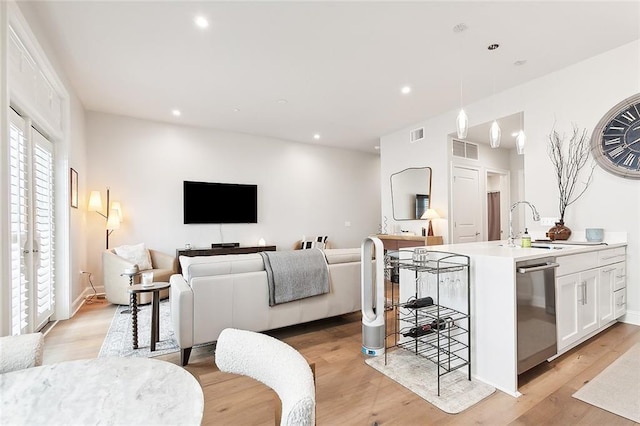 living room featuring sink and light hardwood / wood-style flooring