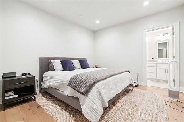 bedroom with connected bathroom and light wood-type flooring