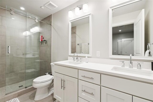 bathroom with double vanity, tile patterned flooring, a shower with door, and toilet