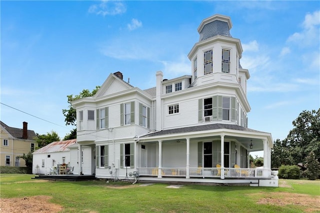 rear view of house featuring a porch and a lawn