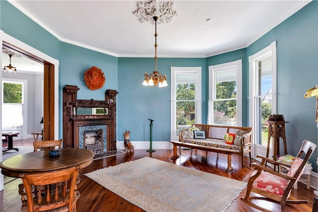 living room featuring hardwood / wood-style floors, a tiled fireplace, ornamental molding, and a chandelier