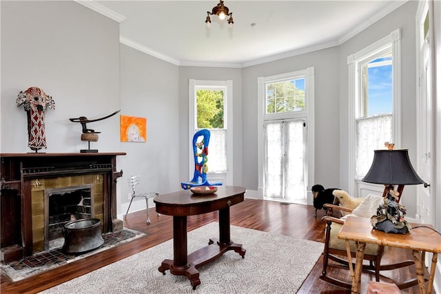 living area with a fireplace, crown molding, and wood-type flooring