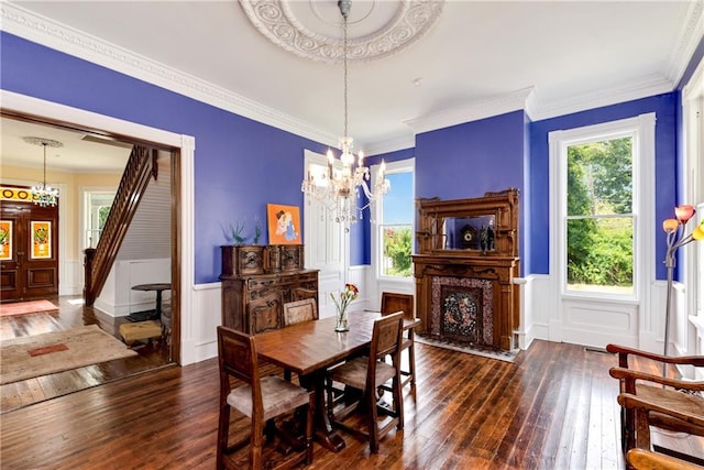 dining room with an inviting chandelier, ornamental molding, dark hardwood / wood-style flooring, and a fireplace