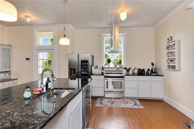 kitchen featuring sink, hardwood / wood-style flooring, wall chimney exhaust hood, range with gas stovetop, and stainless steel fridge with ice dispenser