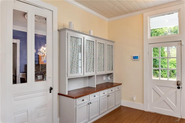 doorway with wood finished floors, baseboards, and ornamental molding