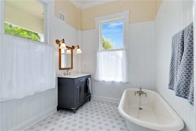 full bathroom featuring wainscoting, vanity, a soaking tub, baseboards, and visible vents