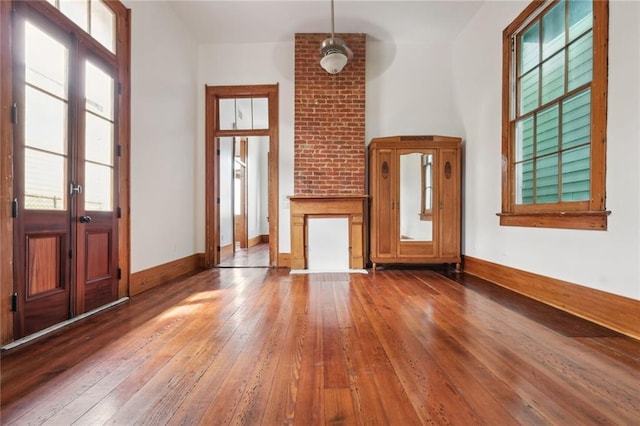 unfurnished living room featuring french doors, wood finished floors, and baseboards