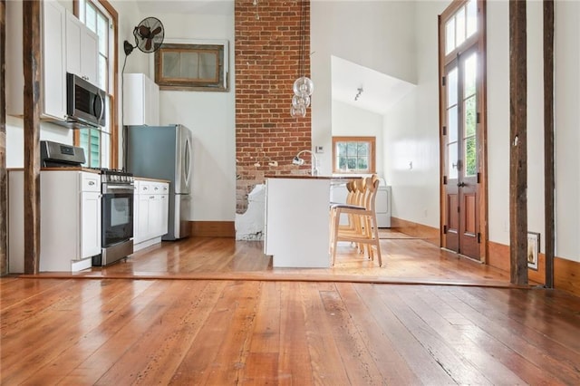 kitchen with white cabinets, light wood-style floors, stainless steel appliances, and a breakfast bar