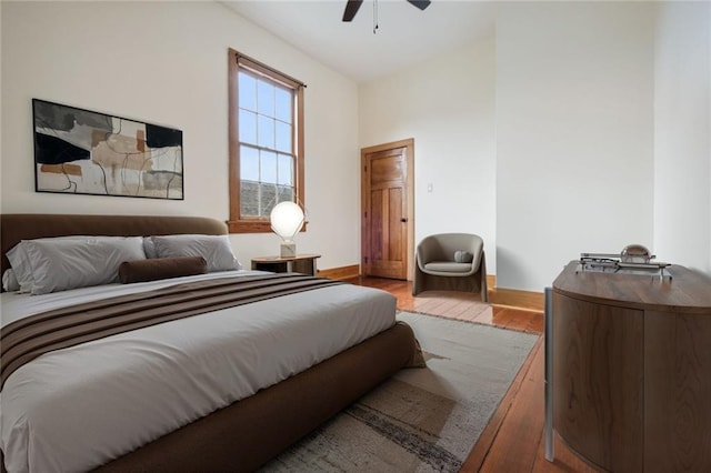 bedroom featuring baseboards, wood finished floors, and a ceiling fan