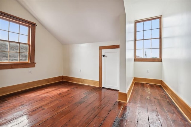 additional living space with dark wood-type flooring, lofted ceiling, and baseboards