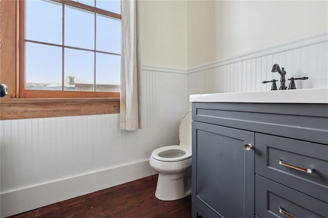 bathroom with a wainscoted wall, vanity, toilet, and wood finished floors