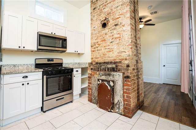 kitchen with visible vents, a ceiling fan, appliances with stainless steel finishes, light stone counters, and white cabinetry