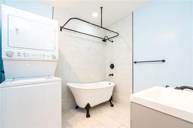 full bathroom featuring a freestanding tub, stacked washer / dryer, and vanity