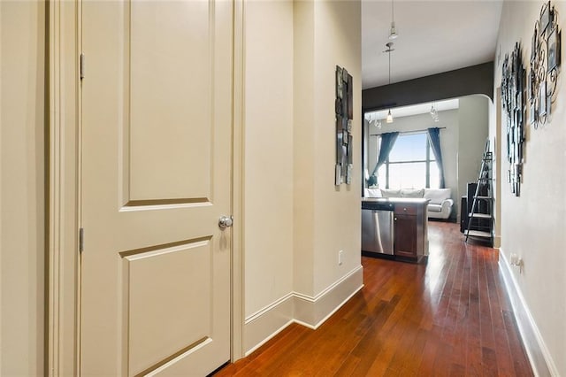 hallway featuring dark wood finished floors and baseboards