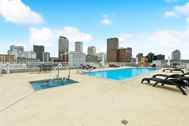 community pool featuring a view of skyline, fence, and a patio area