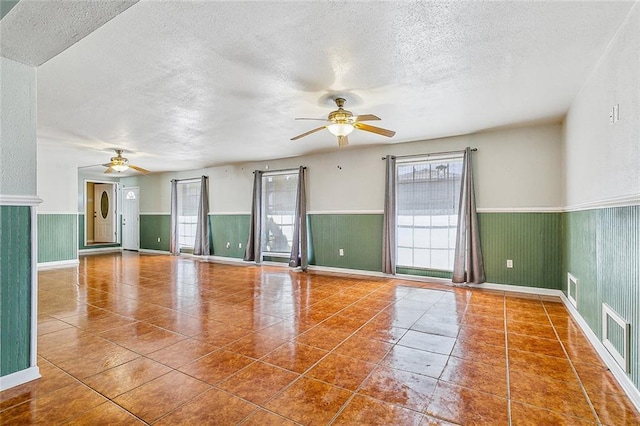 tiled spare room with ceiling fan and a textured ceiling