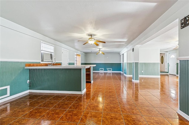 kitchen with dark tile patterned floors, sink, ceiling fan, and kitchen peninsula