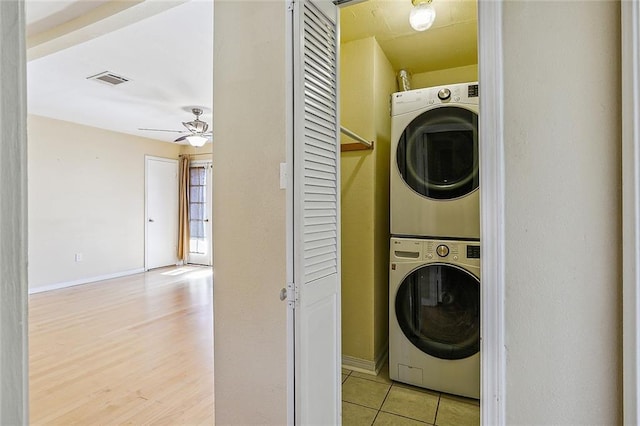 laundry room with ceiling fan, stacked washer and dryer, and light tile patterned flooring