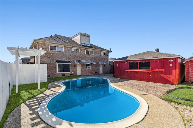 view of swimming pool with an outbuilding and a pergola