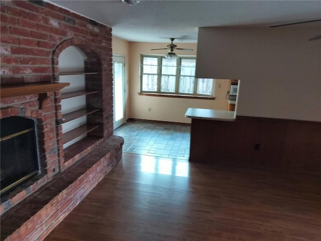 unfurnished living room with a fireplace, dark hardwood / wood-style floors, and ceiling fan