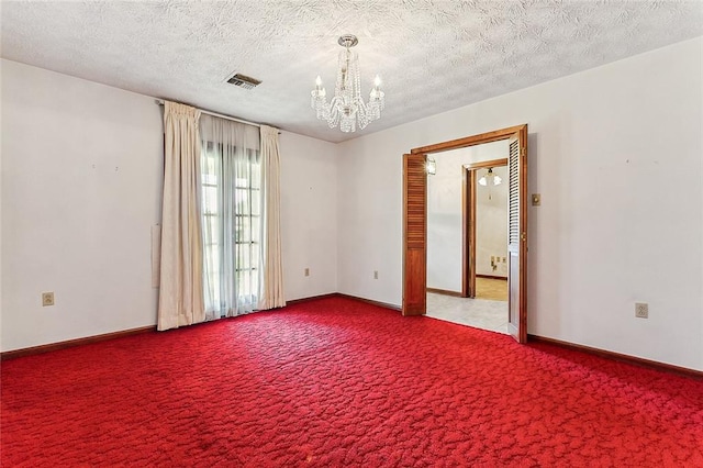 carpeted spare room with an inviting chandelier and a textured ceiling