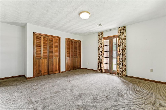 116 Villary St, Belle Chasse, LA 70037 - unfurnished bedroom with two closets, carpet flooring, french doors, and a textured ceiling