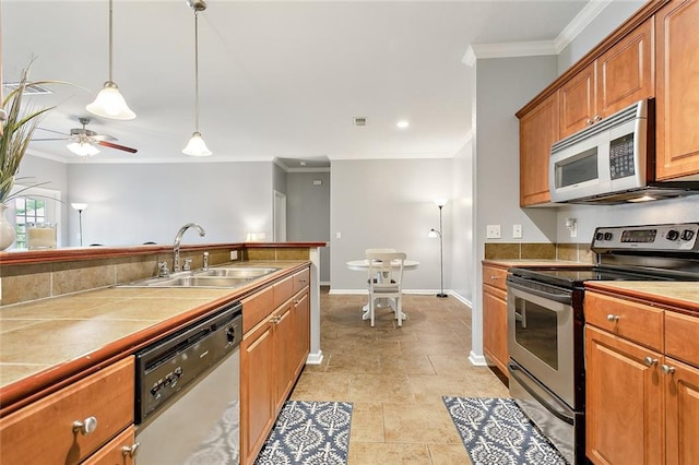 kitchen featuring sink, appliances with stainless steel finishes, ornamental molding, decorative light fixtures, and tile countertops