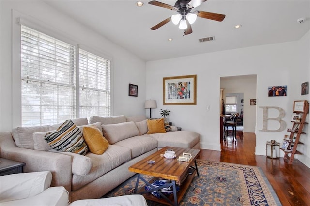 living room featuring ceiling fan and dark wood-type flooring