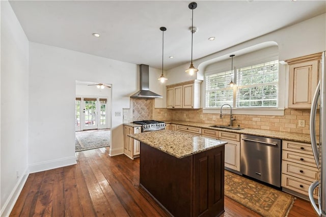 kitchen featuring sink, a kitchen island, wall chimney exhaust hood, stainless steel appliances, and a healthy amount of sunlight