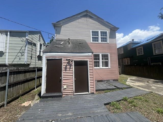 back of property featuring a storage shed and a wooden deck