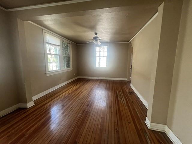 empty room with ceiling fan, dark hardwood / wood-style flooring, and ornamental molding