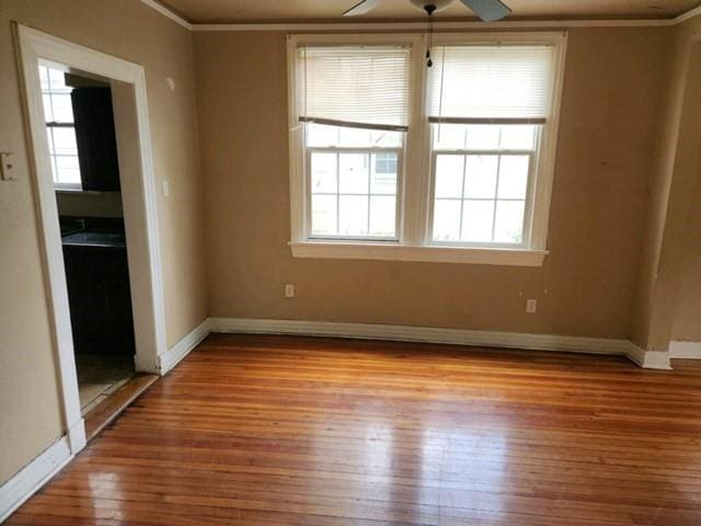 unfurnished room with ornamental molding, ceiling fan, light wood-style flooring, and baseboards