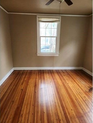 spare room featuring ceiling fan, crown molding, baseboards, and wood finished floors