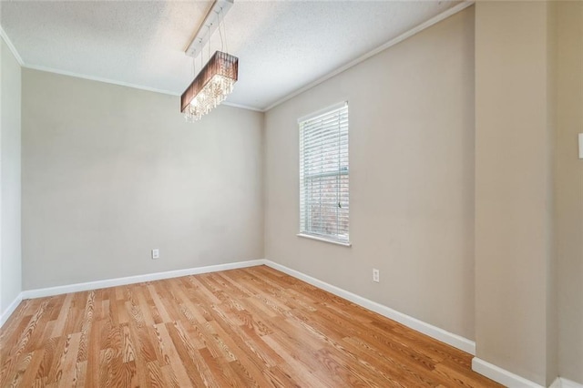 spare room featuring crown molding, a chandelier, light hardwood / wood-style flooring, and a textured ceiling