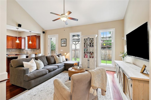 living area featuring a ceiling fan, wood finished floors, and high vaulted ceiling