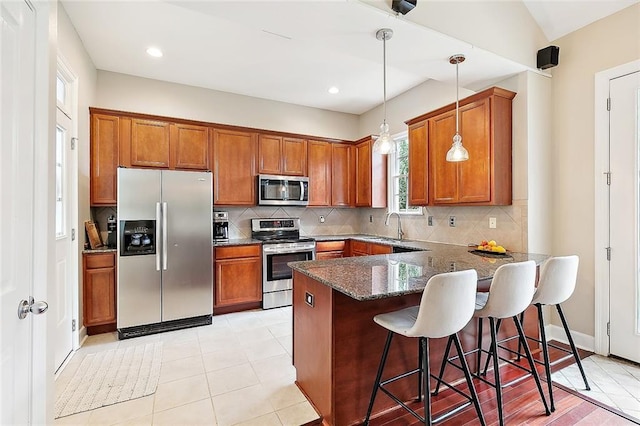 kitchen featuring brown cabinets, appliances with stainless steel finishes, and a peninsula